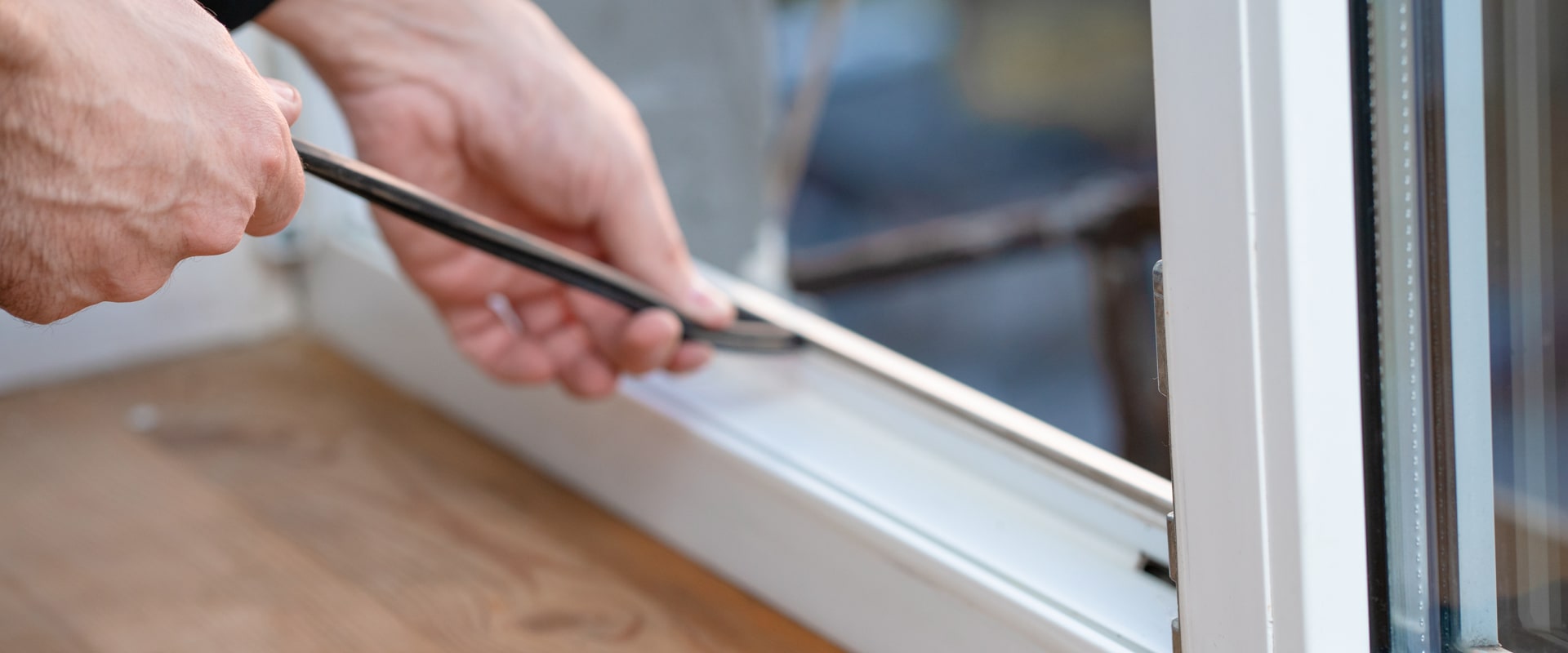 Man removing a rubber seal from a window