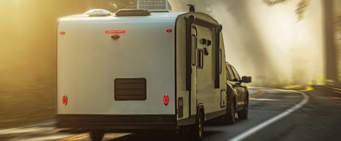 Car towing a caravan driving down the road
