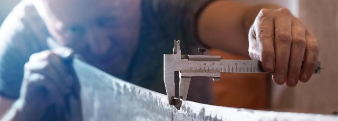 Man using a venier to measure the thickness of aluminium sheet